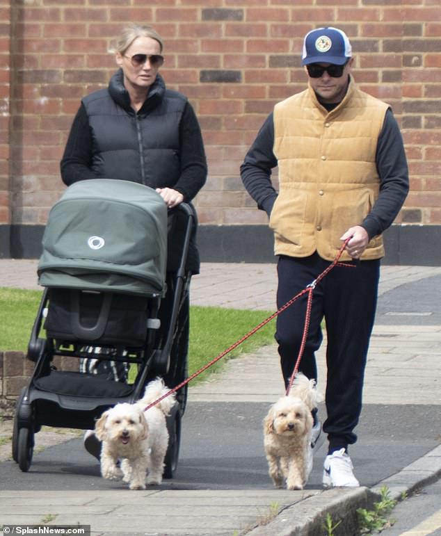 Ant wore a corduroy waistcoat over a black jumper and sweatpants for the walk as he held onto the leashes of their maltipoos Milo and Bumble.