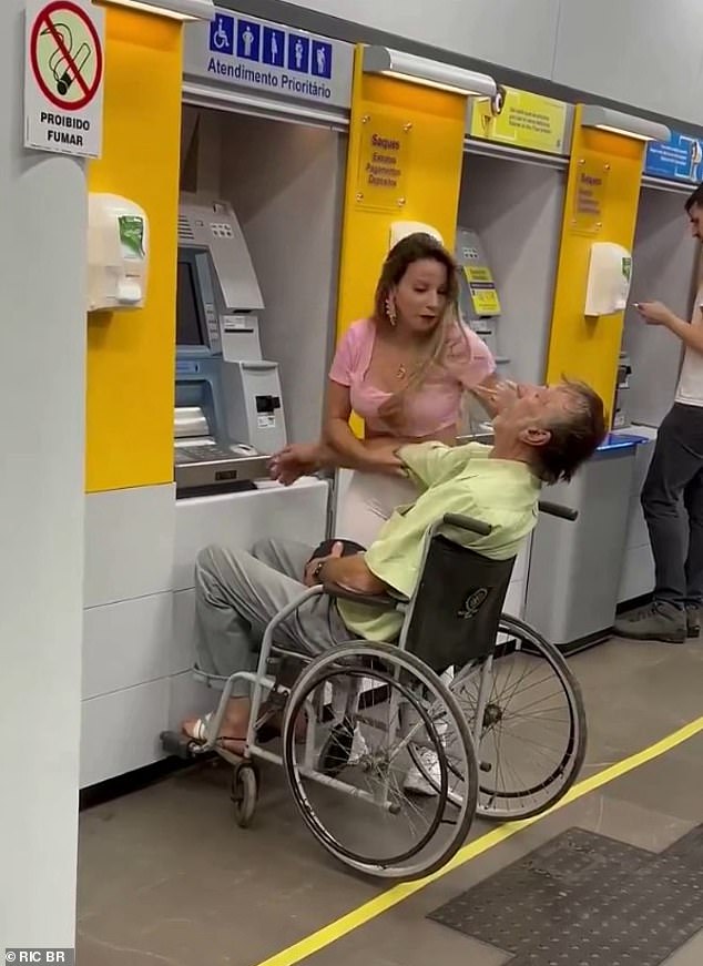 The woman reached back to prevent the man's head from tilting back as she tried to put his finger on the ATM to register his fingerprint and withdraw money