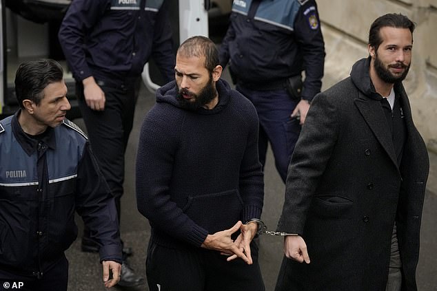 Tate (center) handcuffed to his brother Tristan as he arrived at the Court of Appeal in Bucharest, Romania, in February 2023.  The signal is to help him 'recharge'