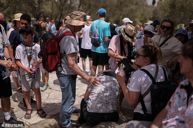 A woman is helped outside the Acropolis archaeological site after feeling unwell