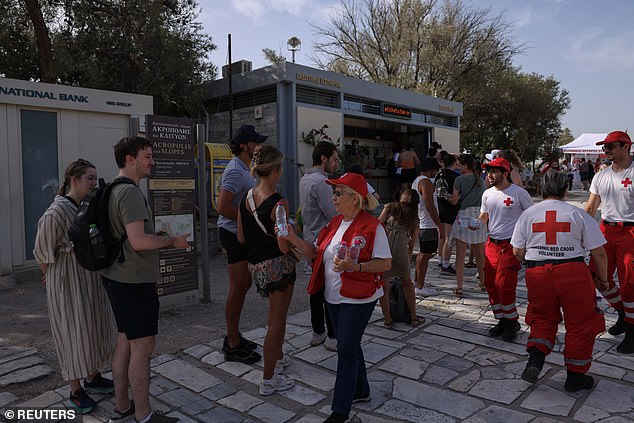 Members of the Greek Red Cross hand over bottles of water to tourists visiting the Acropolis