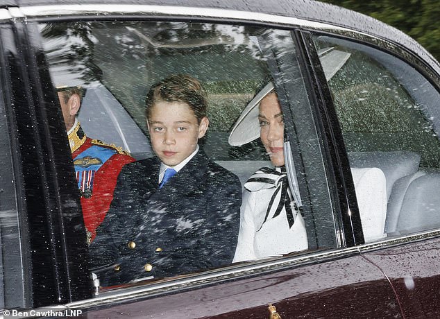 George is sitting in the car in London today between his mother Kate and father Prince William