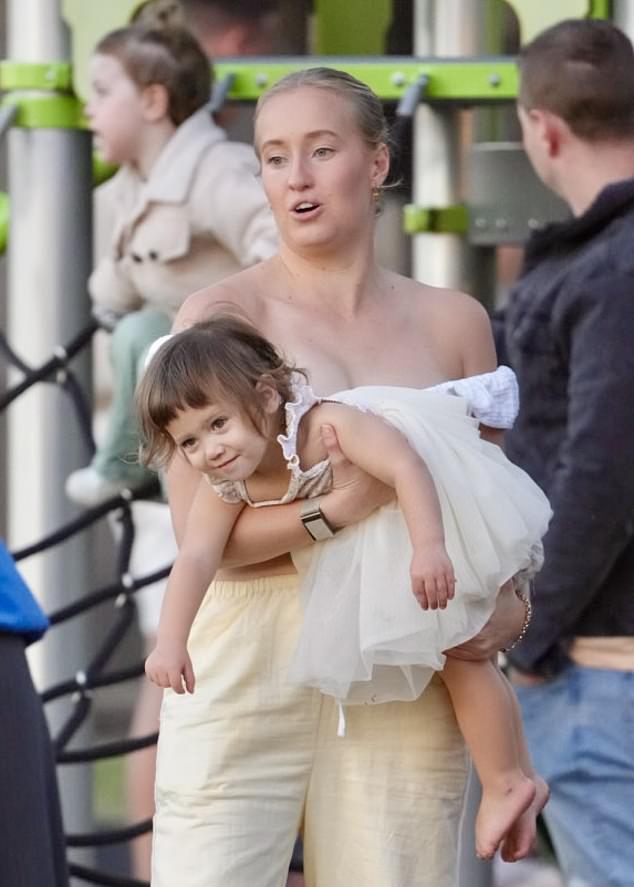 A family friend carried the toddler, who was dressed in a sweet cream-colored dress