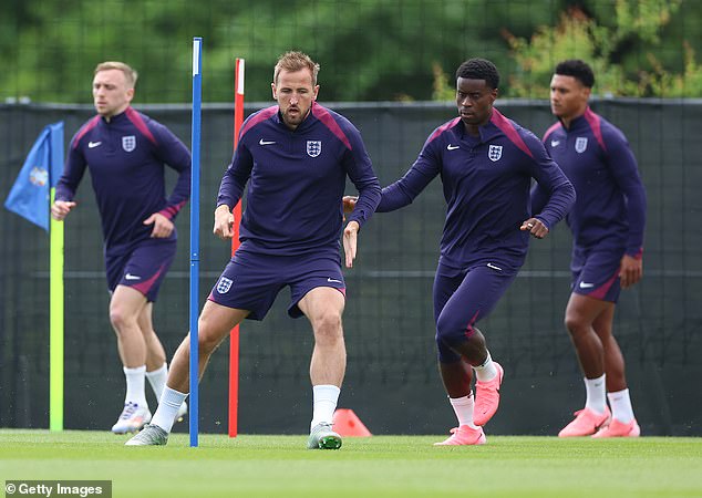 Kane makes his way through a slalom of poles and is closely followed by Crystal Palace star Marc Guehi (right)