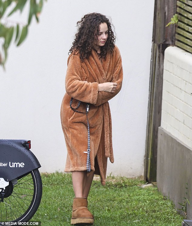 The reality star stayed warm in a brown robe and Ugg boots as she watched as her two dogs sat on the grass