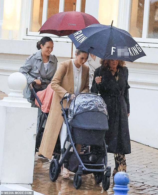 Simone, seen pushing a stroller, looked effortlessly chic in a long beige coat over a white dress
