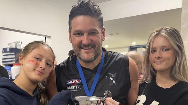 Fevola smiles with the trophy together with his daughters Leni and Lulu after winning a grand final in 2023