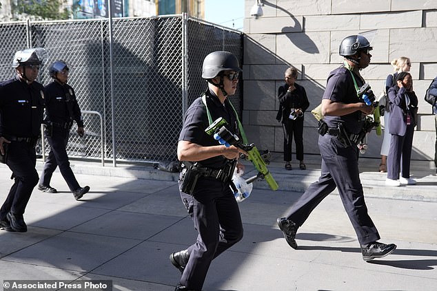 Law enforcement officers carrying less-lethal ammunition respond to protesters near the campaign event with President Joe Biden outside the Peacock Theater in LA on Saturday