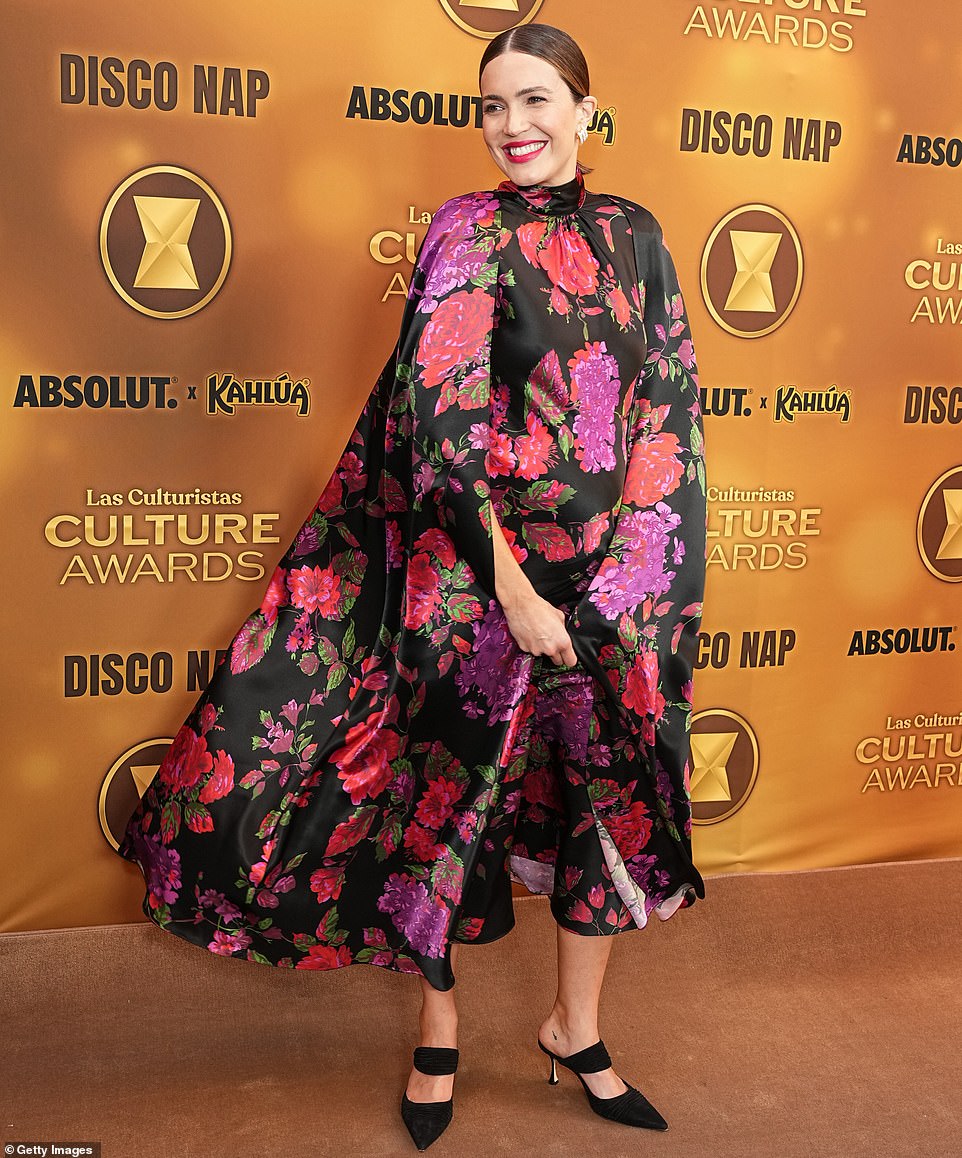 Moore stunned in a black, satin dress with cape fabric cascading down her arms, as well as colorful, floral designs embroidered onto the material