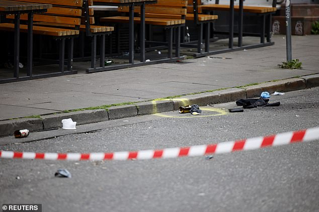 A broken bottle is seen circled with spray paint in a cordoned off area on Silbersackstrasse after an attacker was shot by police