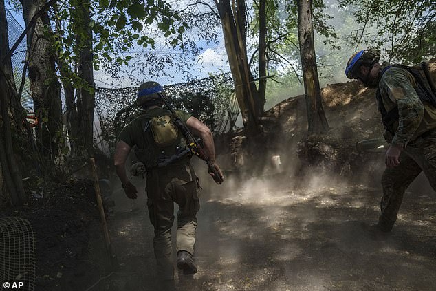 Ukrainian National Guard soldiers from the Khartia Brigade run to reload a D-20 cannon while firing at Russian positions
