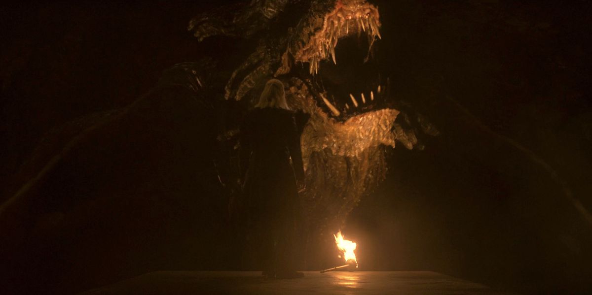 Daemon talks to a large dragon that growls in his face while both are illuminated by torches in House of the Dragon