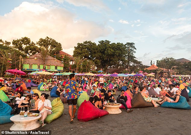 Millions of tourists flock to Bali every year.  The photo shows tourists at a beach bar in Kuta