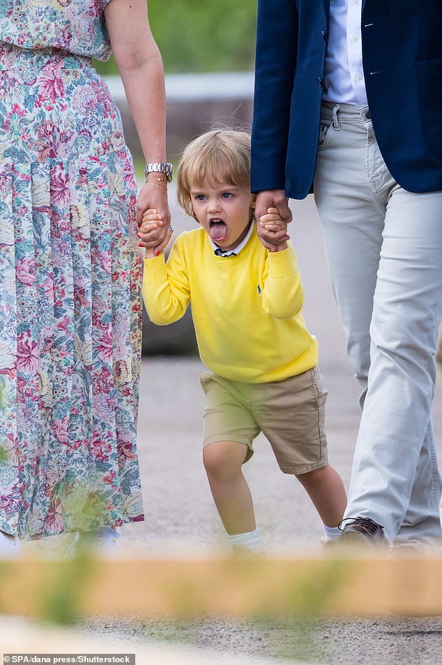 The young Swedish prince showed his cheeky side as he stuck out his tongue while his parents helped him