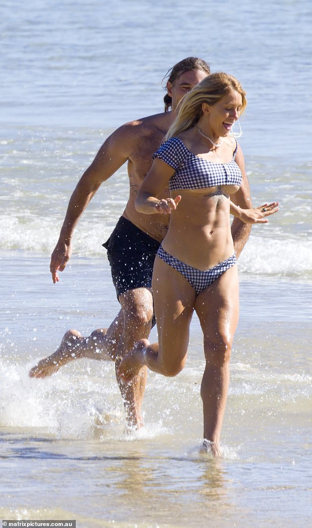 Ali's bikini top showed off her very toned abs and barely clung to her chest as she sprinted away from her cheerful love