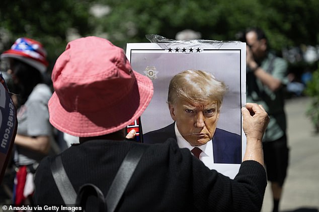 A Trump supporter holding a sign of the ex-president's mugshot outside Manhattan Criminal Court on the day he was convicted on 34 counts of falsifying corporate records