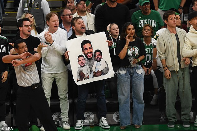 A Celtics fan holds a photo of Tatum, Doncic and Irving that helps describe the series