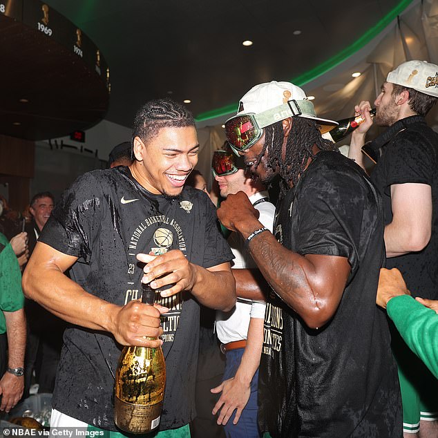 Jaden Springer and Jrue Holiday celebrate with a gold bottle in the Celtics locker room