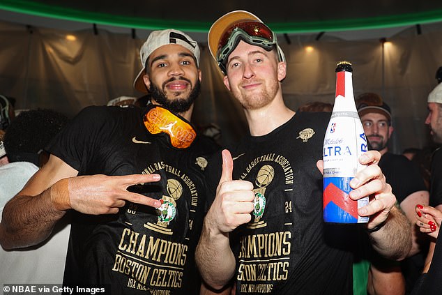 Sam Hauser (right) holds up a beer with Tatum as the Celtics started a long celebration