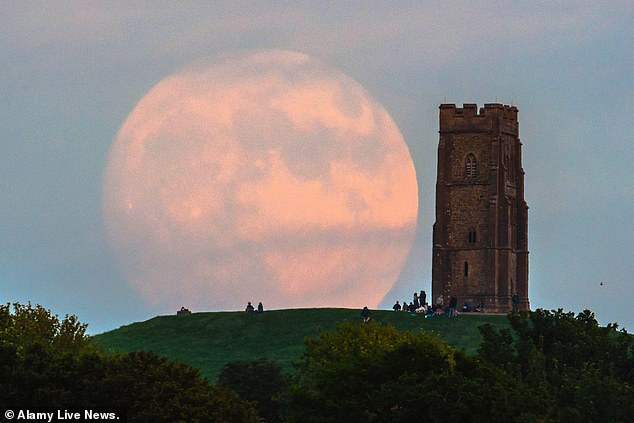 Skygazers should look to the southeast to see the full moon rise over the horizon - and there it will appear large and golden.  Pictured is the 2021 Strawberry Moon in Great Britain