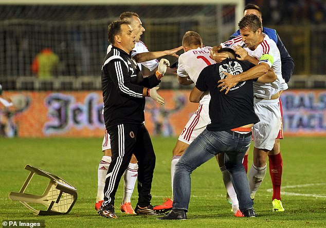 Albanian striker Bekim Balaj is hit by a chair thrown by a Serbian fan as tensions ran high during the Euro 2016 qualifying match