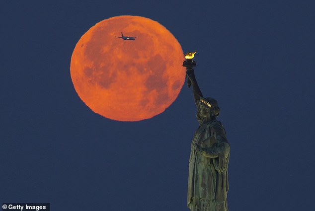Skygazers should look to the southeast to see the full moon rise over the horizon - and there it will appear large and golden.  Pictured is the 2023 Strawberry Moon in New York City