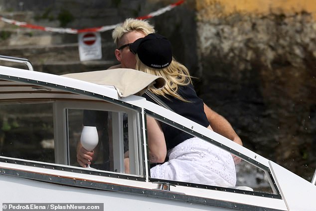 Avril's blonde companion held up a glass of drink as they drove around the lake and exchanged passionate kisses