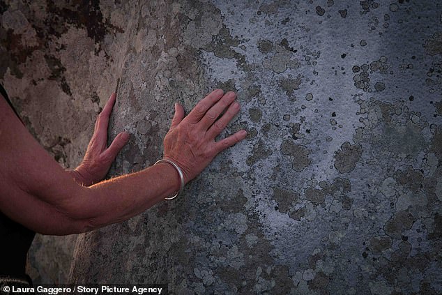 A woman places her hand on the ancient rocks on Thursday evening