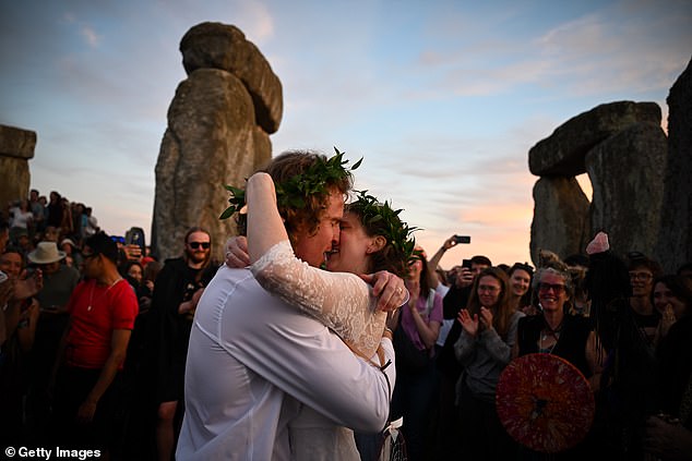 The couple share a kiss as others cheer and take photos