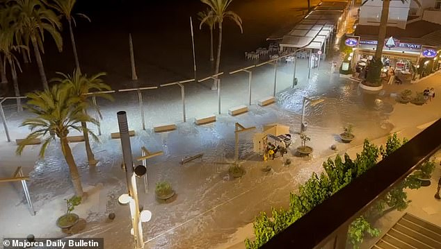 Chairs are seen submerged in the water after the wave in Mallorca as people walk nearby