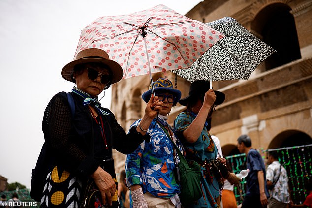 Tourists hold umbrellas to protect themselves from the sun as they walk near the Colosseum amid a heat wave in Rome