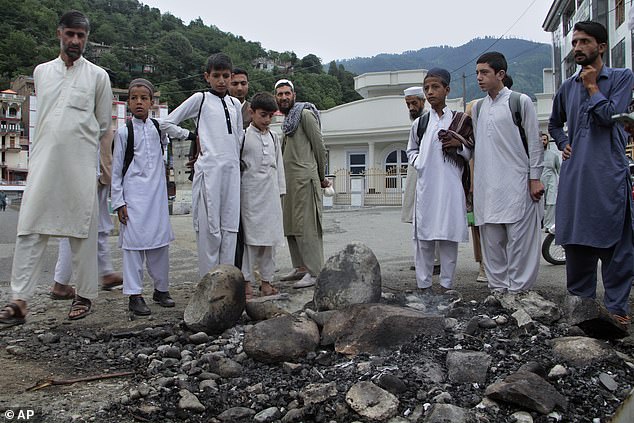 Local residents look at a site where a Muslim mob lynched and burned a man over blasphemy accusations