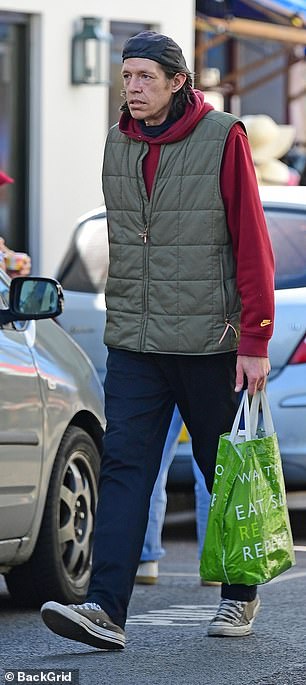 He added a khaki vest to the look and finished the look with a pair of distressed Converse