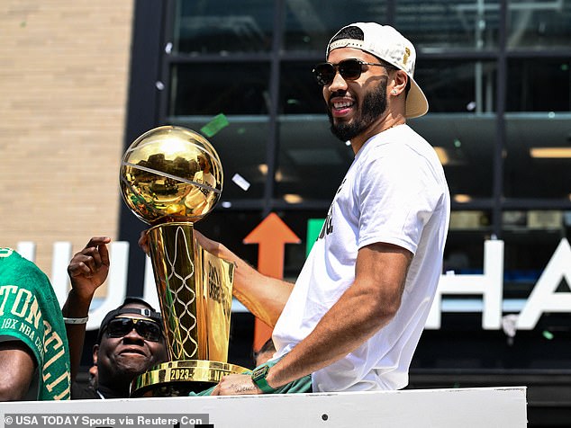 Boston Celtics star Jayson Tatum holds the Larry O'Brien Trophy as he participates in the parade