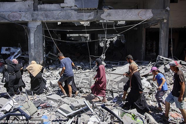People make their way through the rubble of buildings destroyed during the Israeli bombardment of the Al-Shati refugee camp in Gaza City
