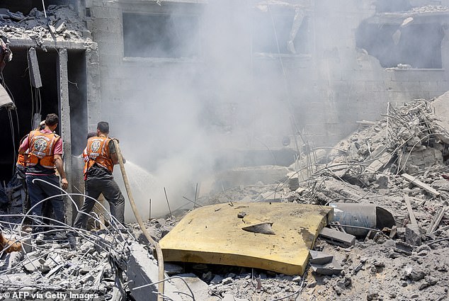 Rescue workers extinguish the flames of a building destroyed during the Israeli bombardment of the Al-Shati refugee camp on Saturday