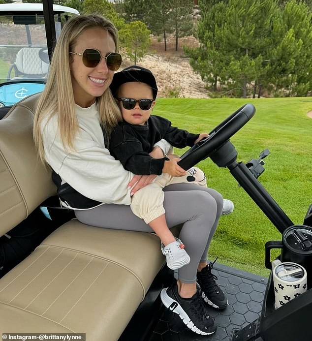 18-month-old Bronzey posed in a golf cart with his mother, wearing sunglasses