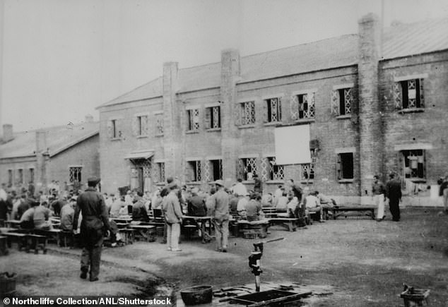 The photo shows prisoners – known as 'maruta', meaning tree trunks – and guards at the death camp