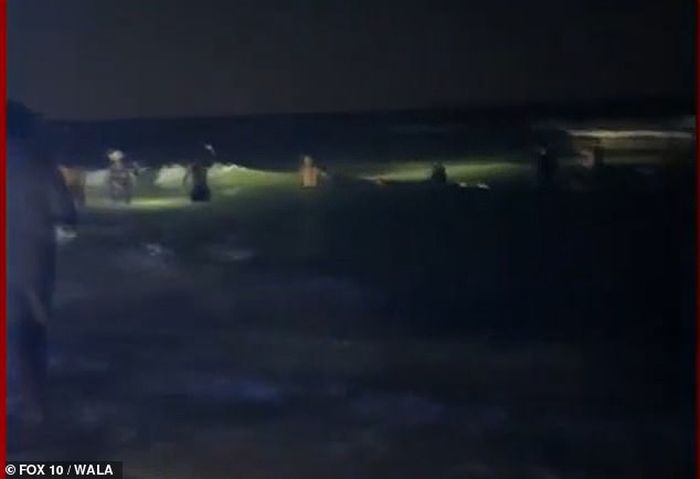 Dozens of volunteers shine their flashlights into the water to assist in the search