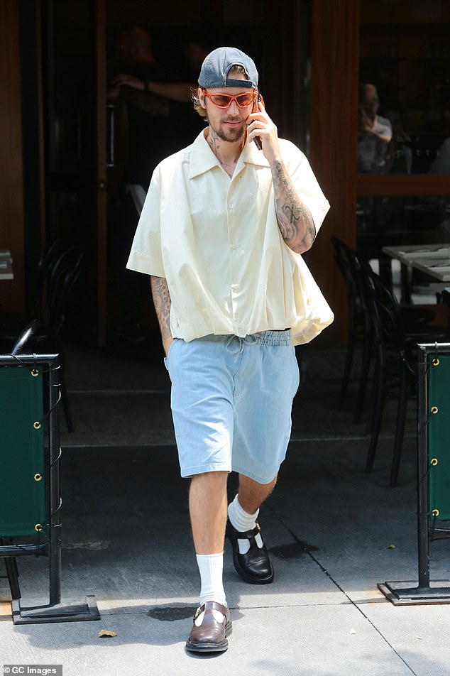 The Canadian pop star wore a casual summer ensemble of a short-sleeved button-up shirt, light blue shorts with an elasticated waist, a gray ball cap and orange sunglasses