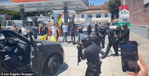 A swarm of police officers dressed in riot gear broke up the chaos with their guns pointed at the protesters and the vehicle