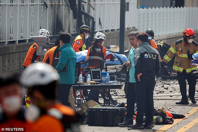 Emergency crews move the body of a person killed in a deadly fire at a lithium battery factory