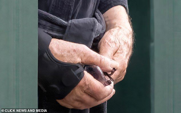 Sir Ian McKellen wears a wrist brace and holds his glasses in his hand yesterday