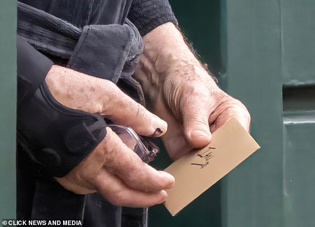 Sir Ian McKellen holds a card with 'Ian' on it as he wears a wrist brace in London yesterday