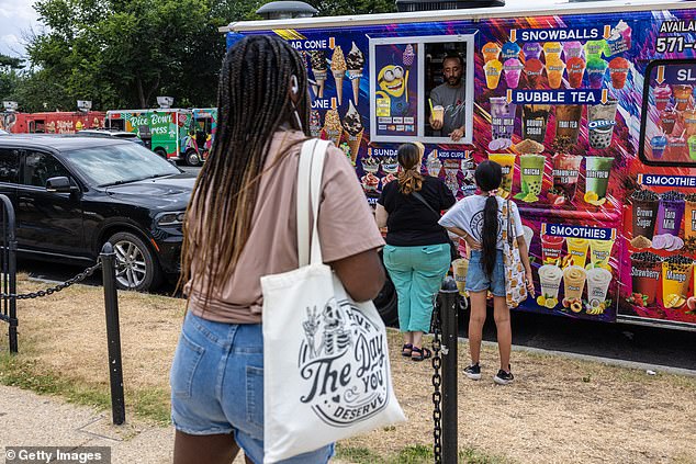 People wait in line for an ice cream truck at the Washington Monument amid a heat wave on the National Mall on June 19