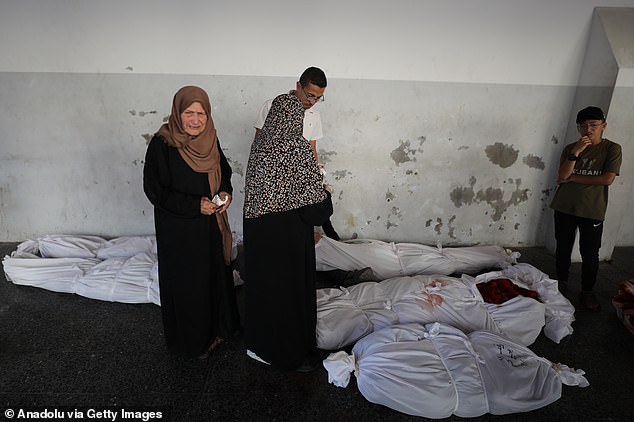 Outraged relatives of the deceased look at body bags of the victims of an air strike