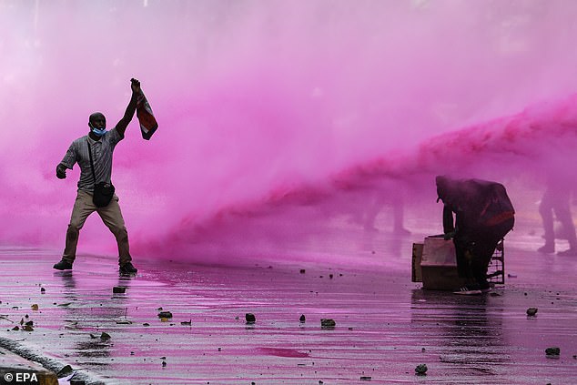 Protesters react as police use water cannon during a protest against proposed tax increases