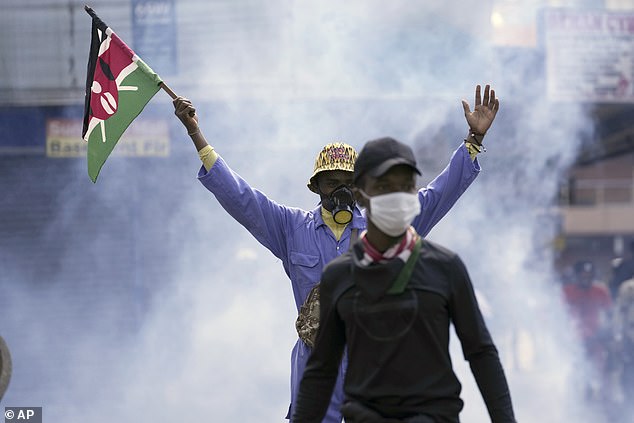 An anti-government protester waves a Kenyan flag as police fire tear gas at them