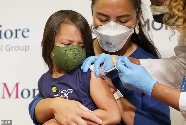 Maria Assisi holds her daughter Mia, 4, as nurse Margie Rodriguez administers the first dose of the Moderna COVID-19 vaccine