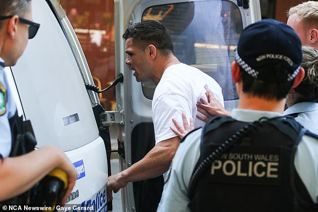 The former Rabbitohs and Panthers star is pictured being led to a police van following a court appearance over the AVO breach last October
